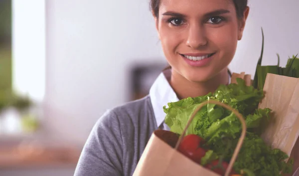 Молодая женщина держит сумку с овощами, стоящими на кухне. — стоковое фото