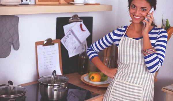 Portrait a smiling woman text messaging of vegetables in kitchen at home — Stock Photo, Image