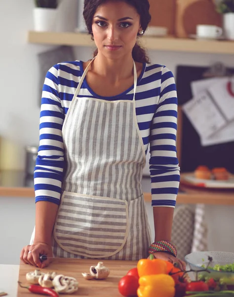 Jeune femme coupant des légumes dans la cuisine — Photo