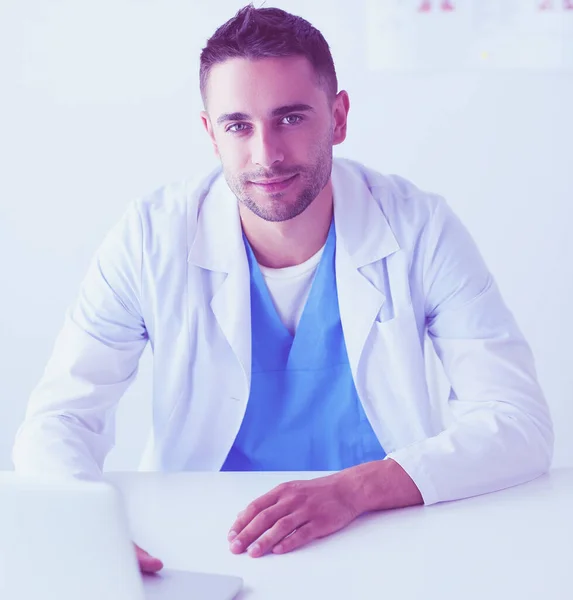 Portrait of a male doctor with laptop sitting at desk in medical office. — Stock Photo, Image