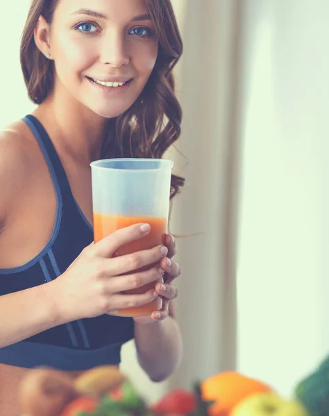 Flicka sitter i köket på skrivbordet med frukt och glas juice — Stockfoto