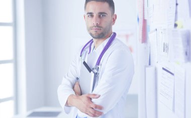 Genç ve kendinden emin erkek doktor portresi tıp ofisinde duruyor..