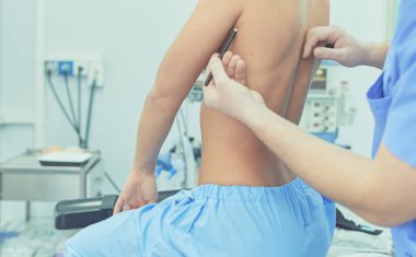 Hastanedeki genç hastaya göğsünü gösteren bir doktor.