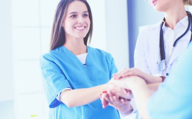 Doktorlar ve hemşireler tıbbi bir ekipte el ele tutuşuyorlar.