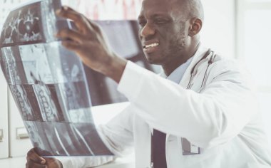 Genç Afrikalı doktor portresi hastaların röntgenlerini tutuyor.