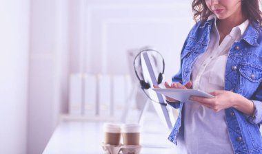 Gülümseyen kadın kahve içiyor ve kafede tablet kullanıyor.