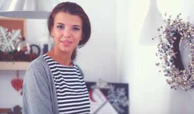 Genç bir kadın mutfakta duruyor.