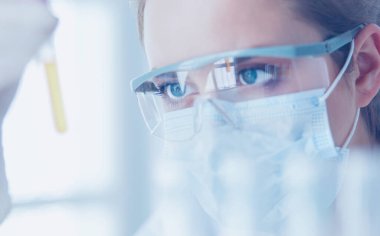 Modern laboratuvar veya hastanede plastik tıbbi tüplerle çalışan araştırmacı, doktor, bilim adamı veya laboratuvar asistanı