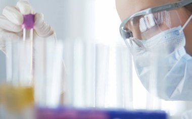 Laboratuvarda sıvı yeşil çözeltiye bakan bir tıbbi veya bilimsel araştırmacı ya da doktor