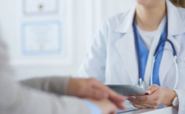 Kadın doktor hastane lobisinde tablet bilgisayar kullanarak, gülümseyerek