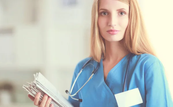 Portrait of woman doctor with stethoscope at hospital corridor, holding a folder. — Stock Photo, Image