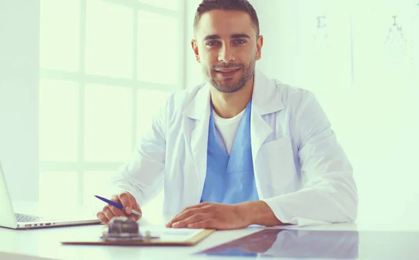 Ritratto di un medico di sesso maschile con computer portatile seduto alla scrivania nello studio medico. — Foto Stock