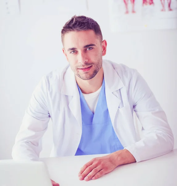 Portrait d'un médecin avec un ordinateur portable assis au bureau médical — Photo