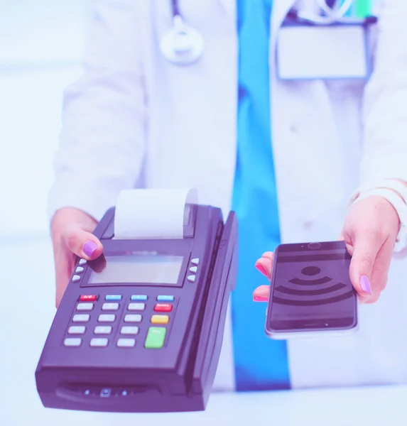 Doktor trzyma terminal płatniczy w rękach. Płacenie za opiekę zdrowotną. Doktorze. — Zdjęcie stockowe