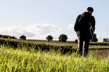 Kırsalda yeşil çimenler ve arkada yürüyen bir adam. 