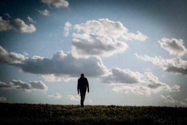 Mavi bulutlu gökyüzünde yürüyen insan silueti