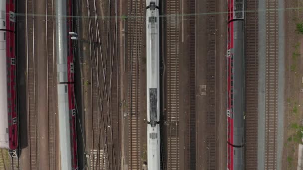 Aerial Overhead Top Down View of Passenger Train On Multi Track Lane with Power Lines and other parked Train Wagons — Stock Video