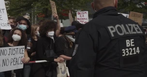 Офицер полиции Германии с толпой на фоне демонстрации против расизма и жестокости полиции в Берлине 6 июня 2020 года — стоковое видео