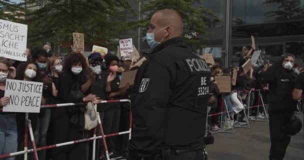 German Police Officer wearing mask with Crowd of young people in Background behind barricade at Demonstration against Racism and Police Brutality in Berlin Germany on June 6th 2020 — Stock Video