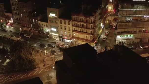 AERIAL: Aufnahme einer Straßenkreuzung mit Autoverkehr und Street Food Markt in der Nacht in Chinatown, Manhattan, New York City — Stockvideo