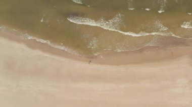 Sahilde yürüyen bir çift ya da arkadaşlar Dalgaların çarpmasıyla vuruldular