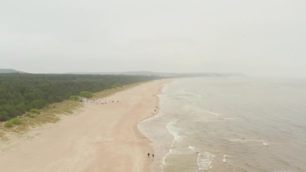 AERIAL: Vuelo sobre nublado nebuloso mar Báltico playa con bosque verde y playa — Vídeo de stock