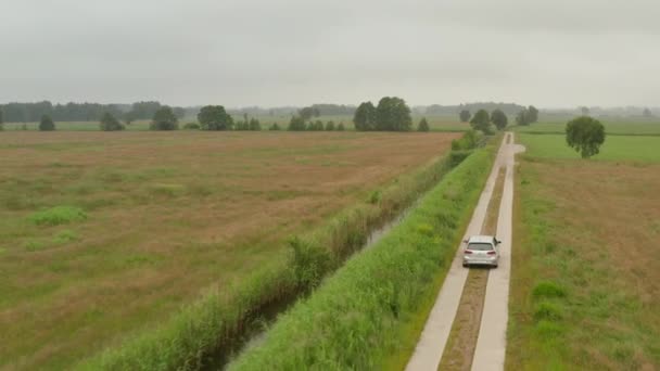 フォギー・オーバーキャスト・デイでドイツ自然界の水によって道路を走行する電気自動車の空中フォローショット — ストック動画