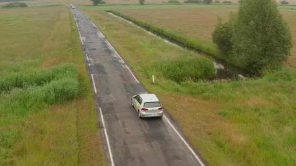 Luchtfoto van elektrische auto rijden over kleine landweggetjes in de Duitse natuur op mistige bewolkte dag met inkomend verkeer — Stockvideo
