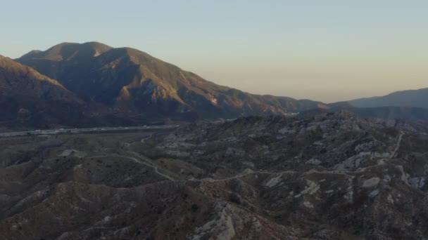 空気:日没時にカリフォルニア州側のハイウェイと山の上 — ストック動画