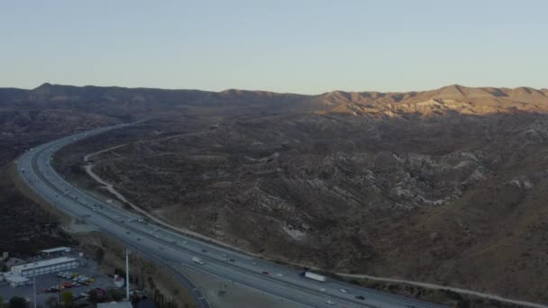 AERIAL: Carretera en el campo de California con montañas en Beautiful Sunset — Vídeos de Stock