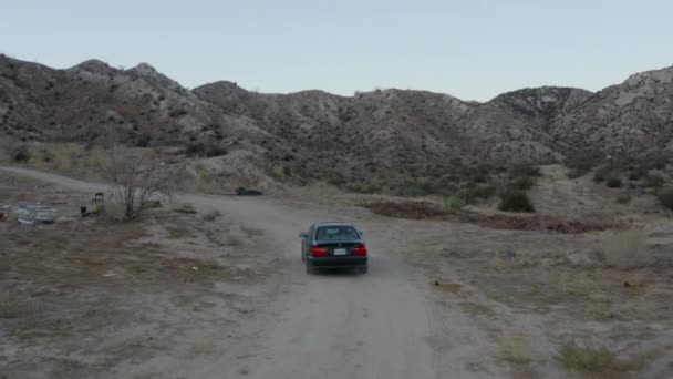 AERIAL: Volg shot van zwarte auto rijden door woestijn in Californië, Daglicht — Stockvideo