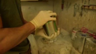 Atölyedeki ressam yeşil renkte bir kutu sallıyor