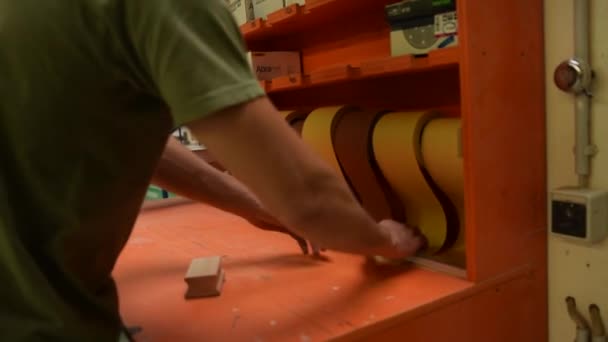Männlicher Arbeiter in seiner Werkstatt reißt ein Stück Sandpapier ab