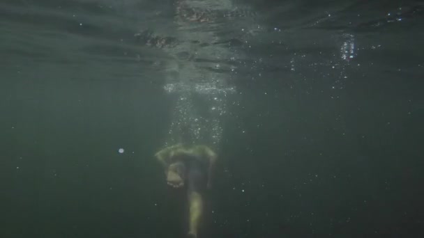 Yavaş hareket, suyun altında genç erkeğin yüzüşünü, dalışını. — Stok video