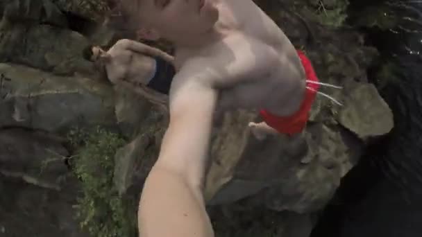 Реакція повільного руху пролунає з обриву молодого дорослого скелета, який стрибає у воду — стокове відео