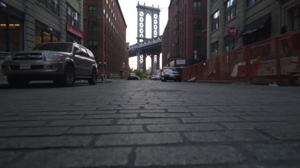 SLOW MOTION: Brooklyn Bridge Vista da Dumbo con case vacanza dumbo e auto parcheggiate di lato in estate alla luce del mattino presto — Video Stock