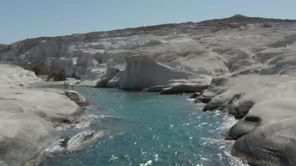 Luftflug durch den wunderschönen Sarakiniko Lunar Volcanic Beach Canyon mit Touristen im Wasser auf der Insel Milos, Griechenland — Stockvideo