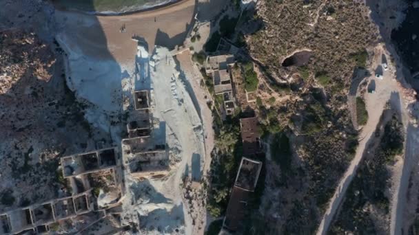 Visão aérea aérea do olho das aves de cima para baixo de uma aldeia abandonada da fábrica na praia na ilha grega — Vídeo de Stock