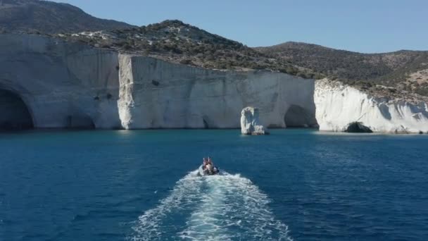 ホワイトパラダイス崖に向かって青い海のモーターボートの空中フォローショット — ストック動画