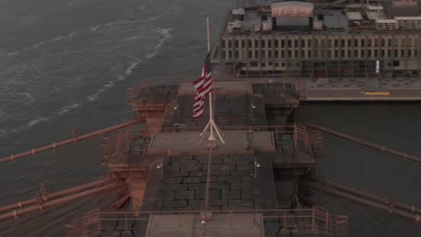 AERIAL: 미국 국기와 안개낀 맨해튼 시 스카이 라인으로 브루클린 다리 상공에서 원 비행을 마무리하는 모습 — 비디오