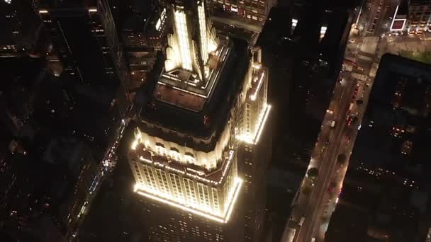 AERIAL: lélegzetelállító kör felett ikonikus Empire State Building felett világított párhuzamos utak és csomópontok lakóházak és irodaházak Midtown Manhattan, New York City éjjel — Stock videók