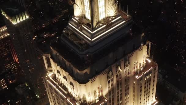 Epic close up heli shot του Empire State Building άναψε παράλληλα λεωφόρους και διασταυρώσεις κατοικίες και κτίρια γραφείων στο Midtown Manhattan, Νέα Υόρκη τη νύχτα — Αρχείο Βίντεο