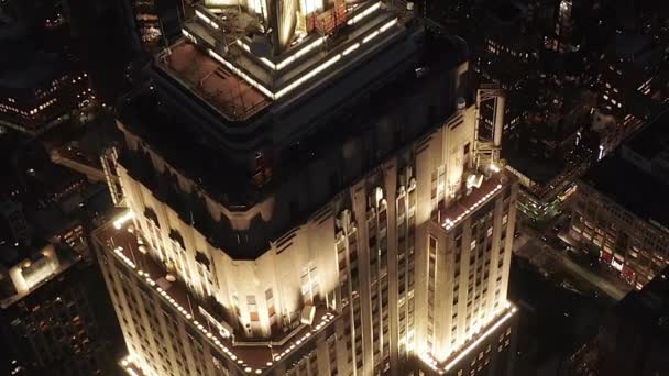 AERIAL: Breathtaking flight over the iconic Empire State Building above lit up parallel avenues and junctions residential condominiums and office buildings in Midtown Manhattan, New York City at night — Stock Video