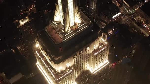 AERIAL: Impresionante círculo sobre el icónico Empire State Building arriba iluminado avenidas paralelas y uniones condominios residenciales y edificios de oficinas en Midtown Manhattan, Nueva York por la noche — Vídeo de stock