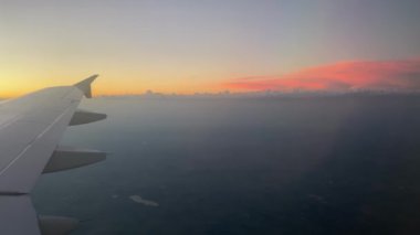 Güneşin doğuşundaki uçak kanadının görüntüsü Bulutların üstündeki ışık