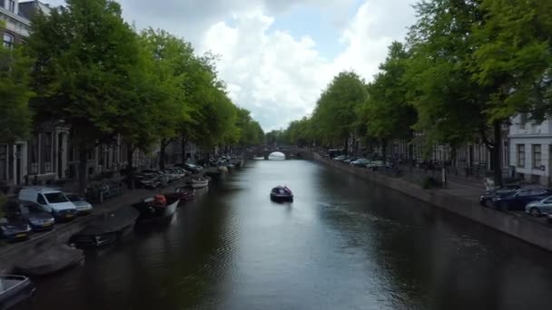 Amsterdam-Kanal mit Boot und holländischer Flagge, die im Wind weht, Vorwärtsantenne — Stockvideo