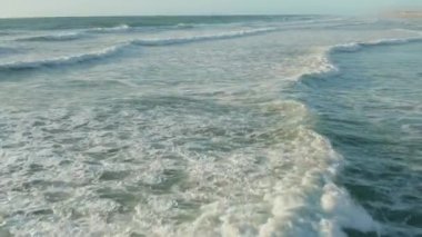 Beyaz köpüklü kusursuz dalgalar güzel bir öğleden sonra ışığı ve berrak bir gökyüzü, havadan düşük açılı bir bebek.