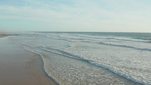 Weinig Surfers op leeg strand met perfecte golven in Sunset licht en wit schuim golven, Luchtfoto naar voren Vestiger — Stockvideo