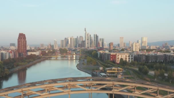 Fráncfort del Meno, Alemania Rascacielos Skyline Vista lenta Dolly hacia fuera revelando puente sobre el río principal al amanecer, Aérea hacia atrás — Vídeo de stock