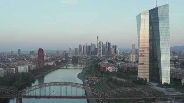 Evropská centrální banka v brzké ranní sluneční odraz a Frankfurt nad Mohanem mrakodrapy v pozadí, Letecký vysoký úhel vpřed, pomalé — Stock video